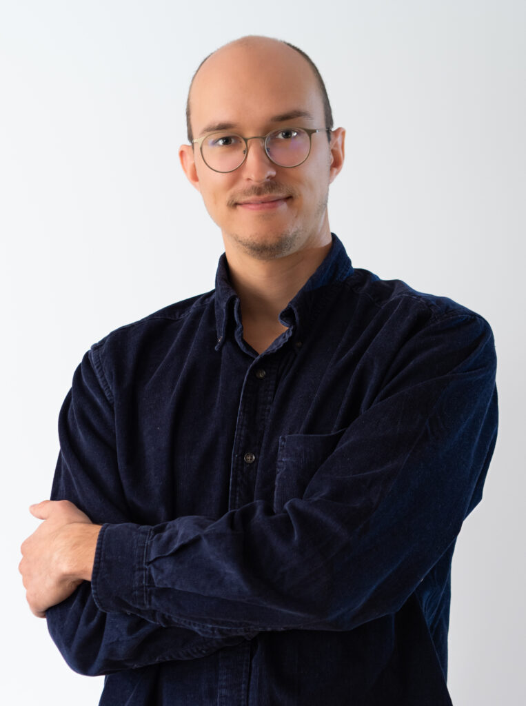 Psychotherapeut mit freundlichem Ausdruck, verschränkten Armen und einem professionellen, einladenden Blick.